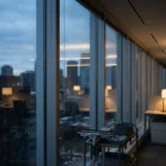 Office window wall admitting blue winter dusk light beside a neatly stored trolley